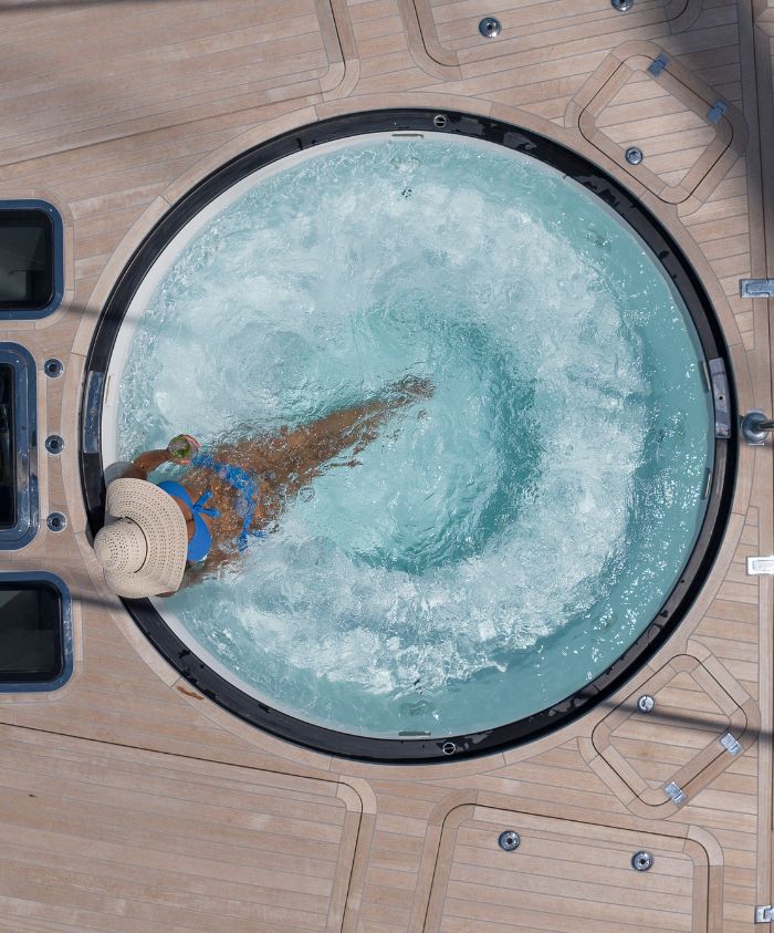 Large sailing yacht deck with woman in blue Jacuzzi