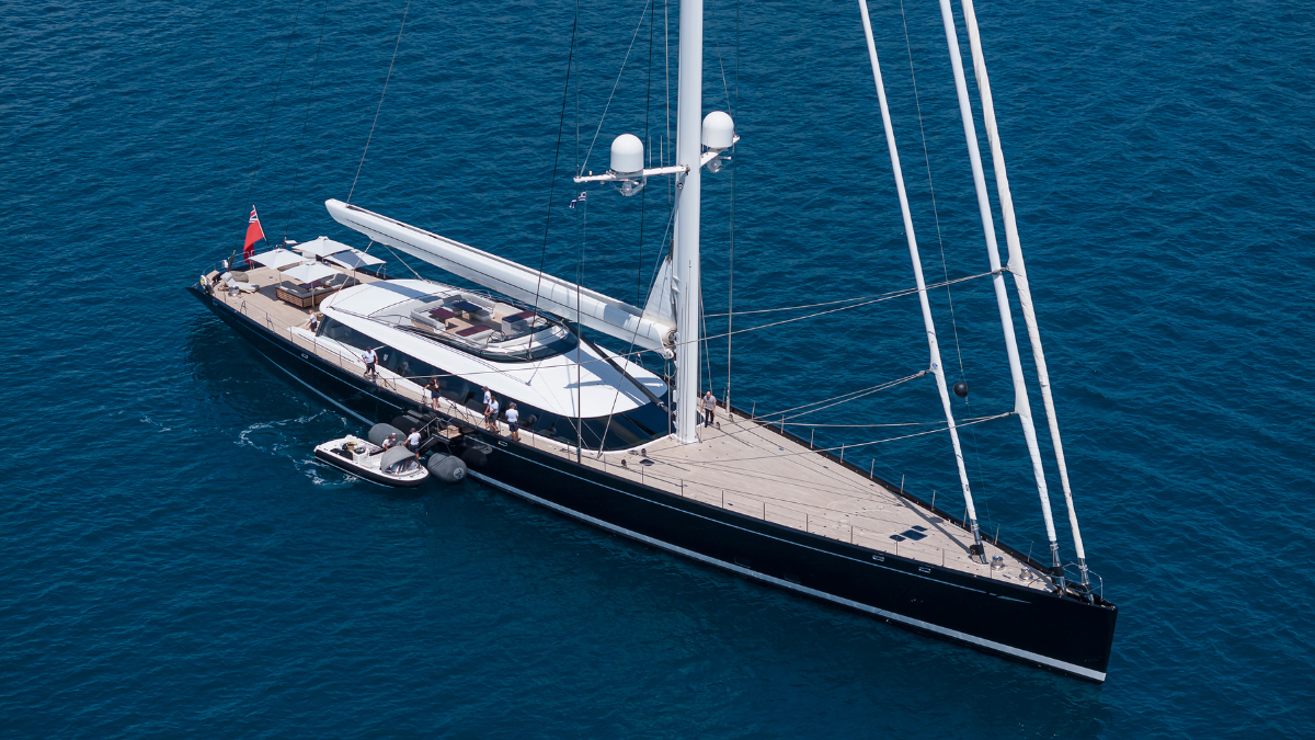 Luxury sailing boat in the blue sea with mast, crew and a small boat next to the yacht