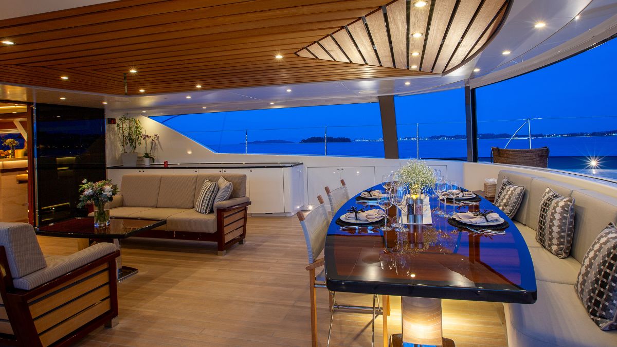 Aftdeck of a large luxury sailing yacht with al fresco dining table, sofas and overlooking the sea