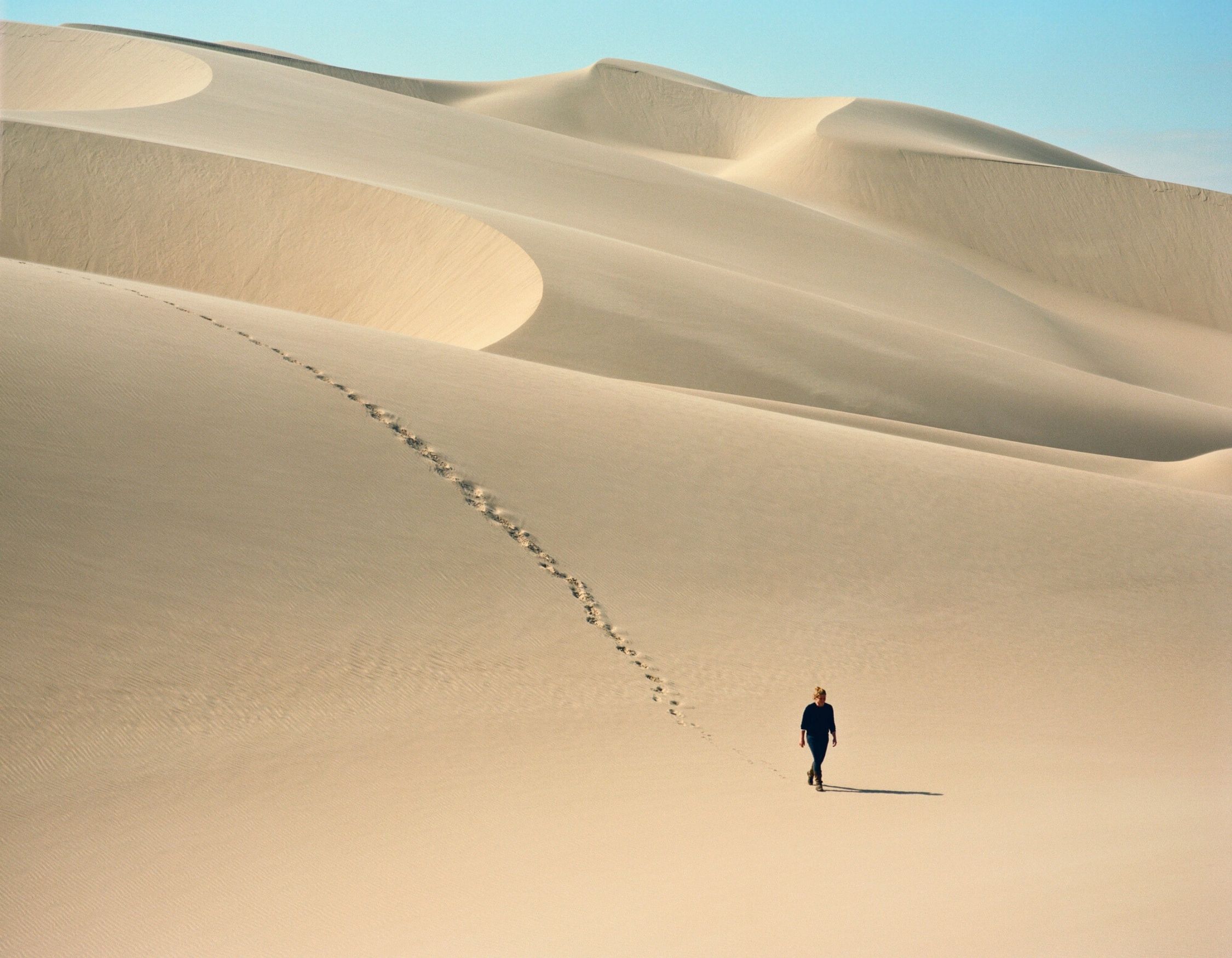 Woman walking alone through the desert sand dunes