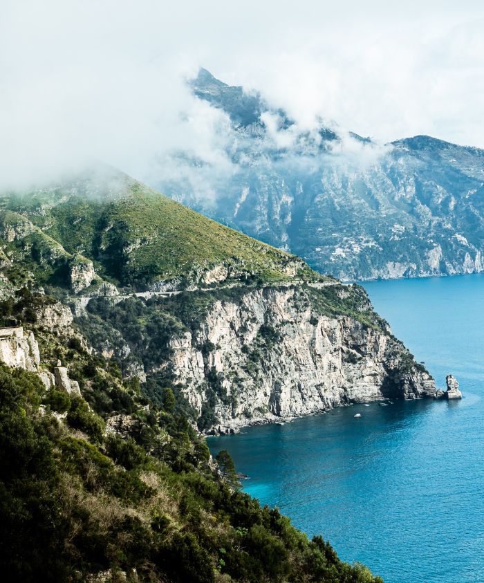 Dramatic green cliffs over turquoise sea in Italy – Pelorus Yachting 2026 Mediterranean luxury yacht charter inspired by the Odyssey.