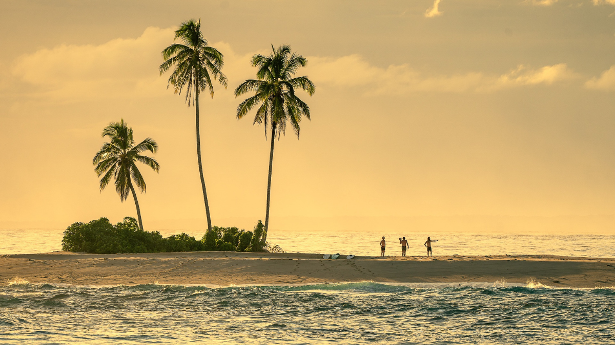 Guests on a remote sandbar at sunset in the Mentawai Islands, Indonesia, accessed by private surf charter yacht SILOINA